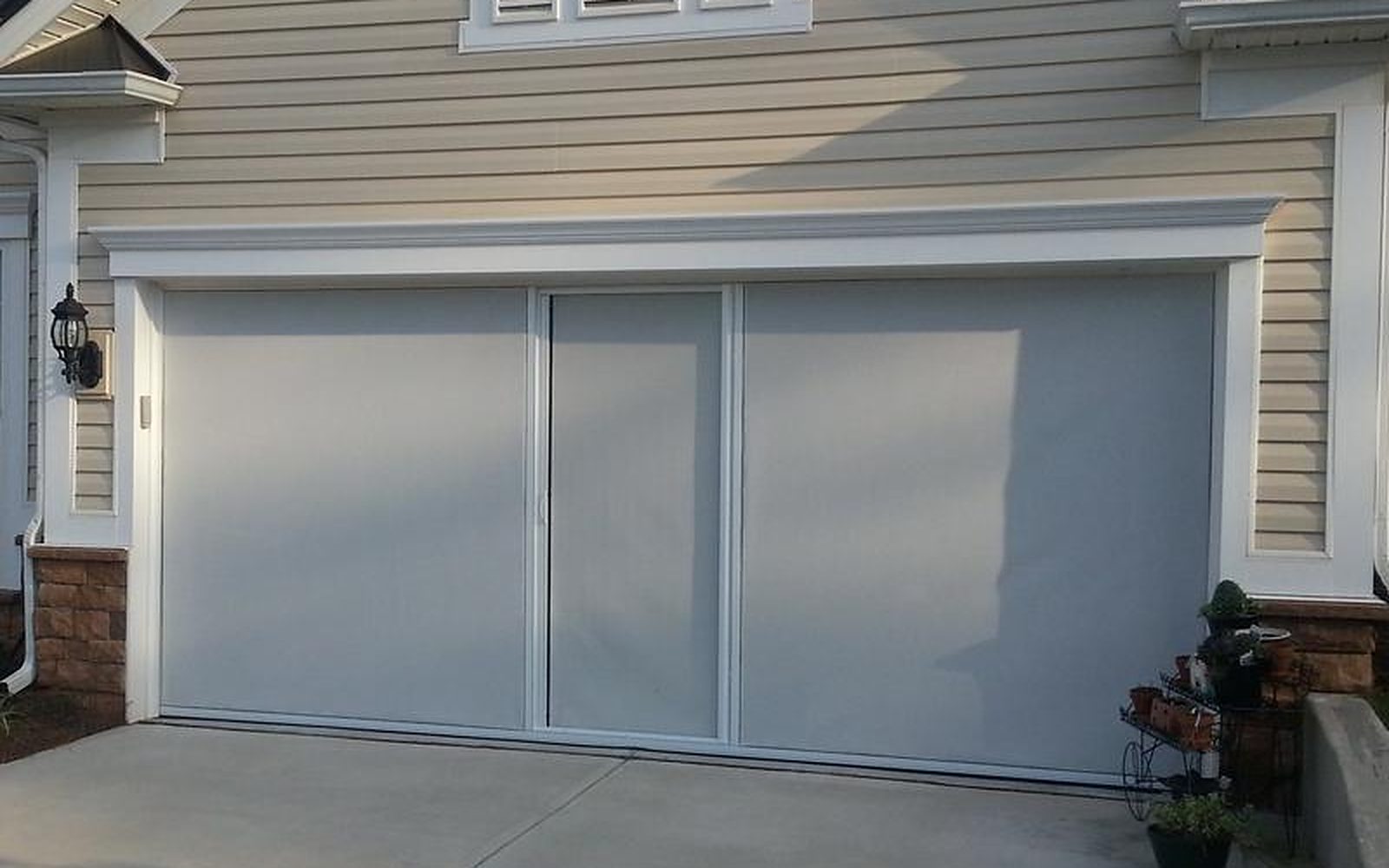 White-framed Lifestyle retractable garage screen with privacy mesh on a two-car garage