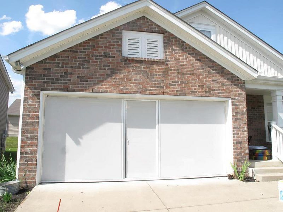 White privacy Lifestyle garage screen lowered across a brick two-car garage