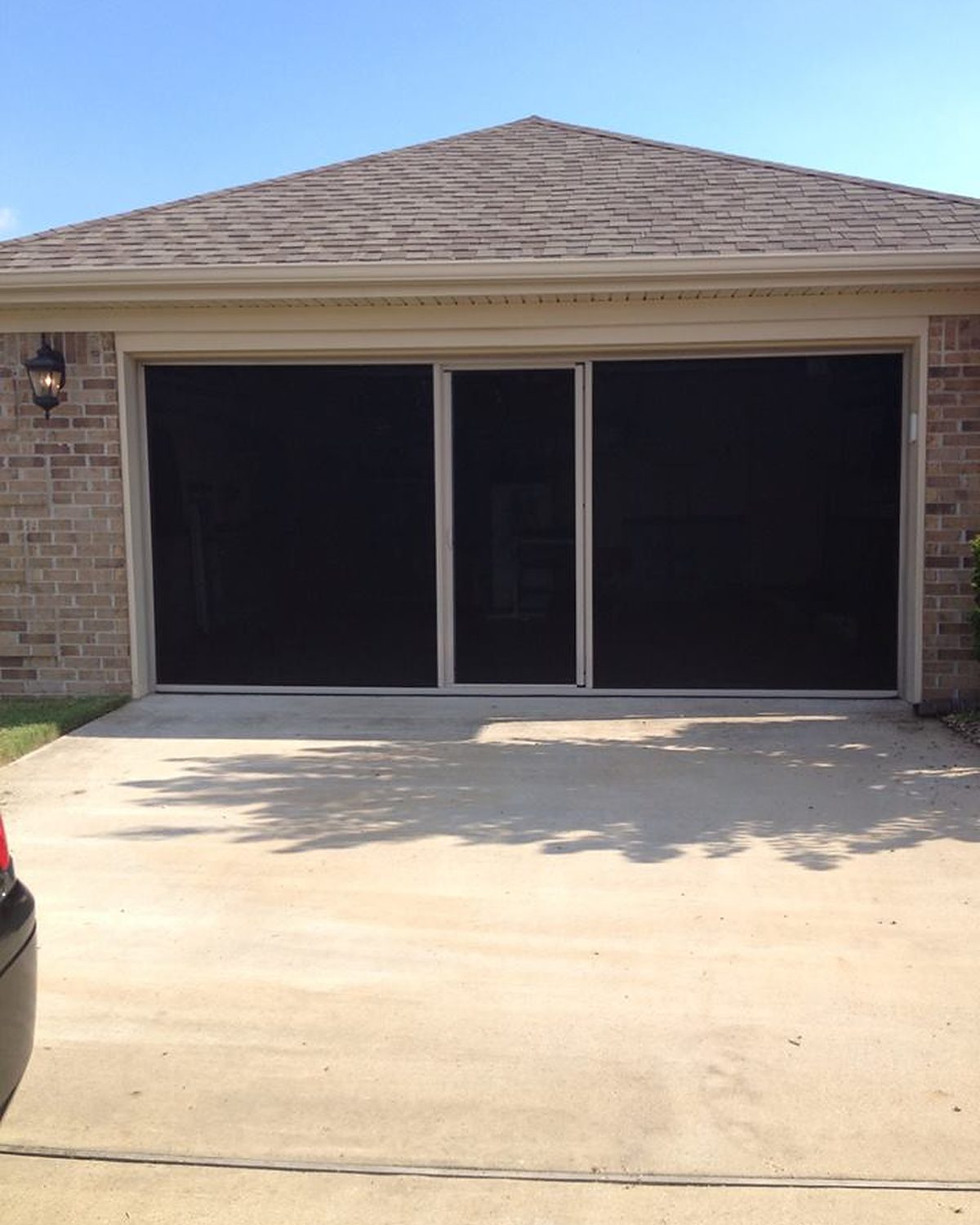 Lifestyle garage screen with charcoal mesh and white frame on a brick single-car garage