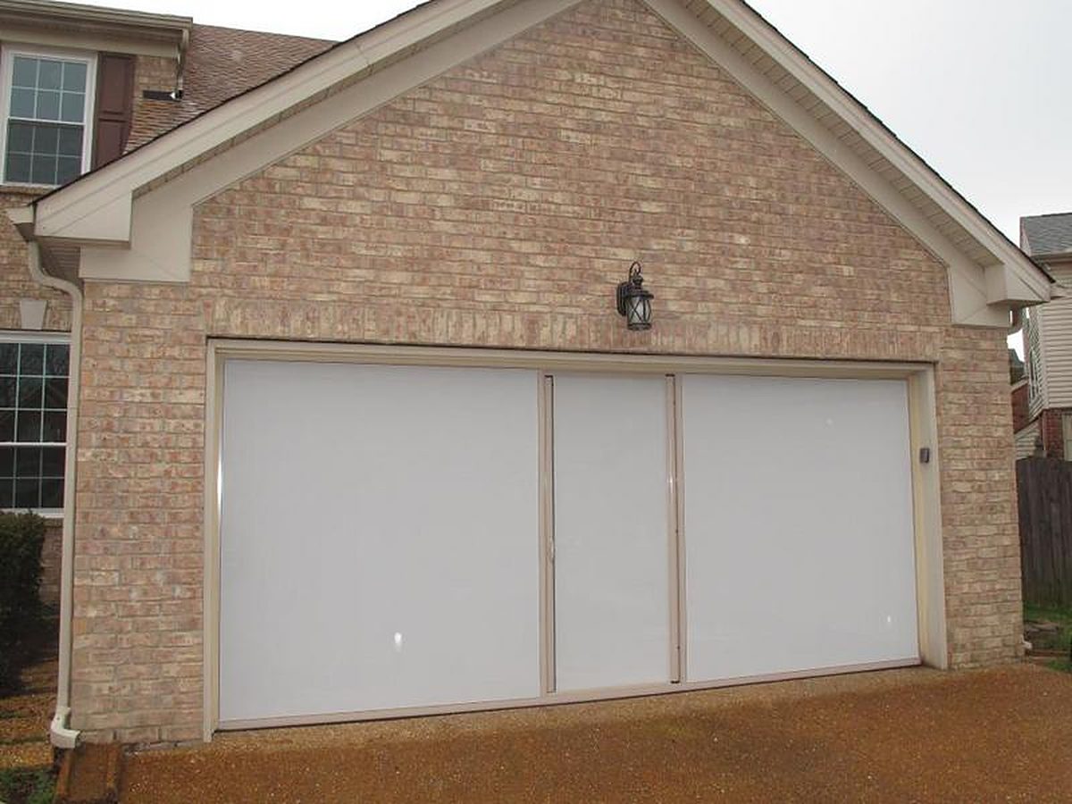 Sandstone-framed Lifestyle retractable garage screen with white privacy mesh on a brick garage