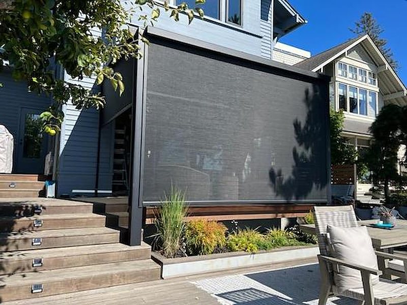 Charcoal motorized screen with black side tracks on a raised wood deck