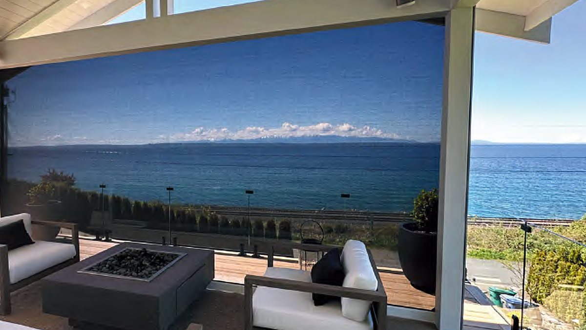 The same covered deck with the motorized screen lowered, the view still visible through the mesh