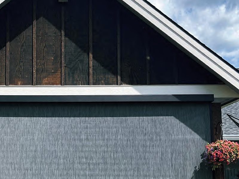 Gray motorized screen lowered across a gabled garage opening
