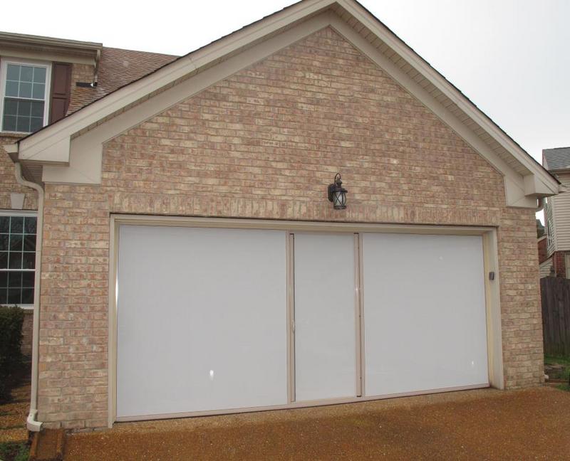 Lifestyle retractable garage screen with sandstone frame and white privacy mesh installed on a home